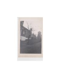 Photograph of a man in tree behind him church and bell tower.