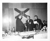 Photograph of celebration at the Ukrainian Hall during Father Zarsky's silver jubilee. Father Zarsky greeting someone with U.C.M.C.