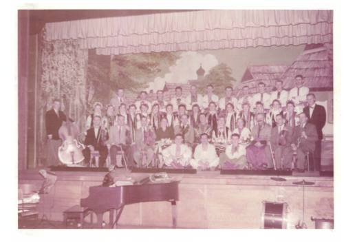 Photograph of performers and orchestra at new Ukrainian Hall with village back drop.